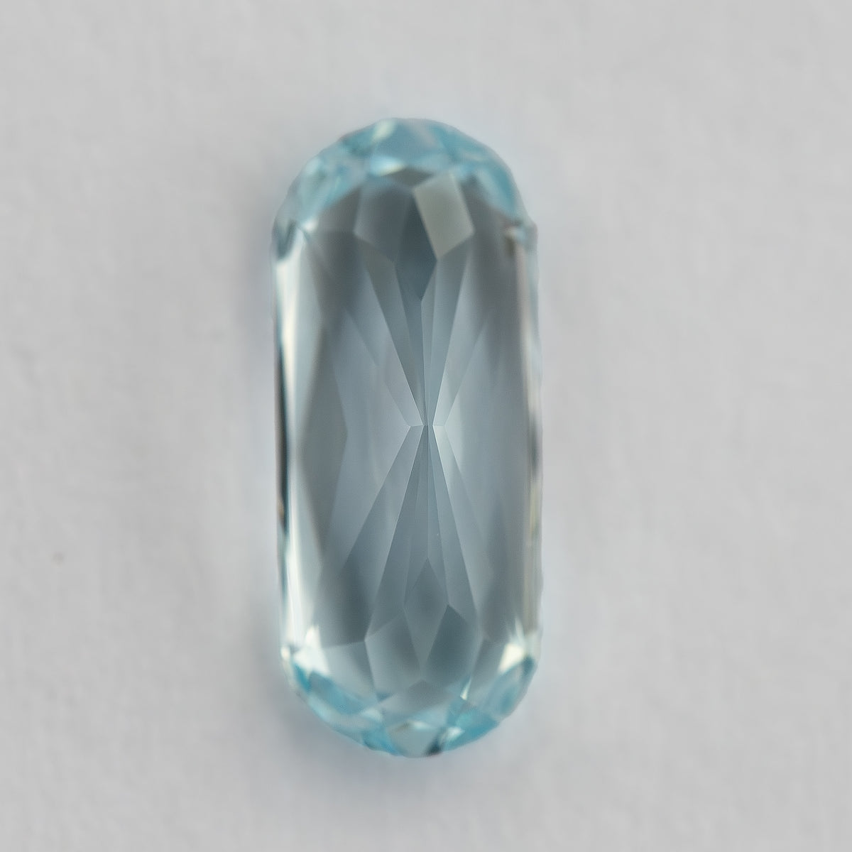 Lengthwise reverse view of the light blue sapphire, with pavilion facets visible.