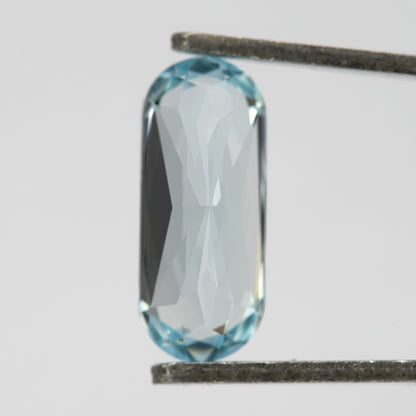 Reverse view of the long-oval sapphire held vertically in tweezers.