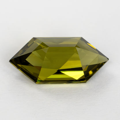Low pavilion-side view of the yellow-green lab-grown sapphire on a white surface.