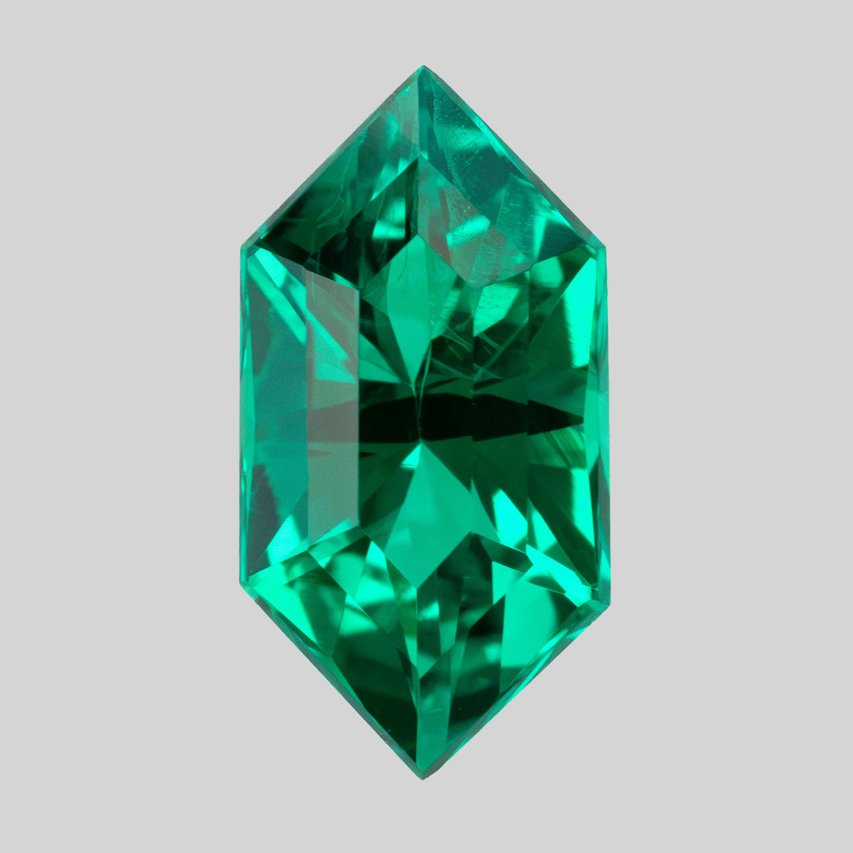Vertical crown view of the green lab-grown emerald against light gray, showing bright and dark facet reflections.