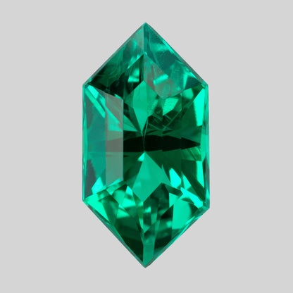 Vertical crown view of the green lab-grown emerald against light gray, showing bright and dark facet reflections.