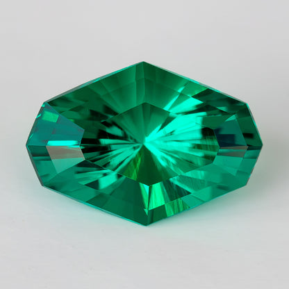 Face-up green octagonal lab-grown emerald on a white background, showing radiating central facets.