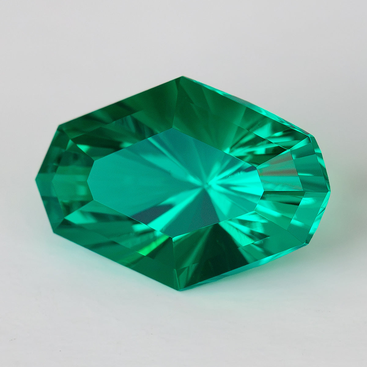 Alternate face-up view of the green octagonal emerald, with a broad bright facet reflection.