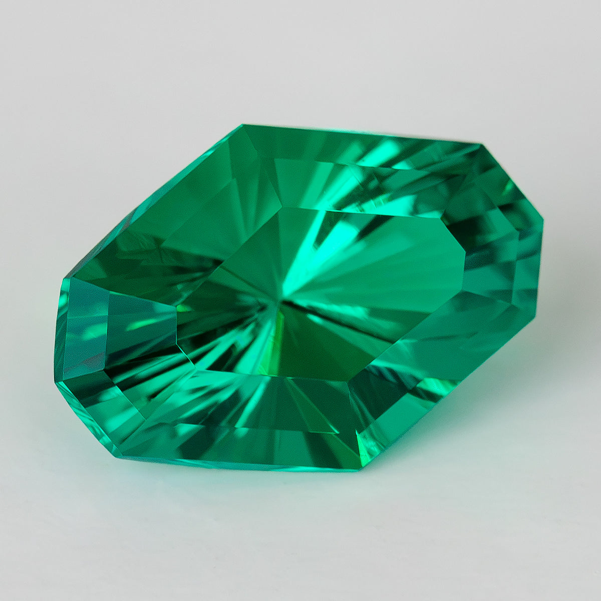 Oblique face-up view showing the green emerald’s eight-sided outline and crossing reflections.