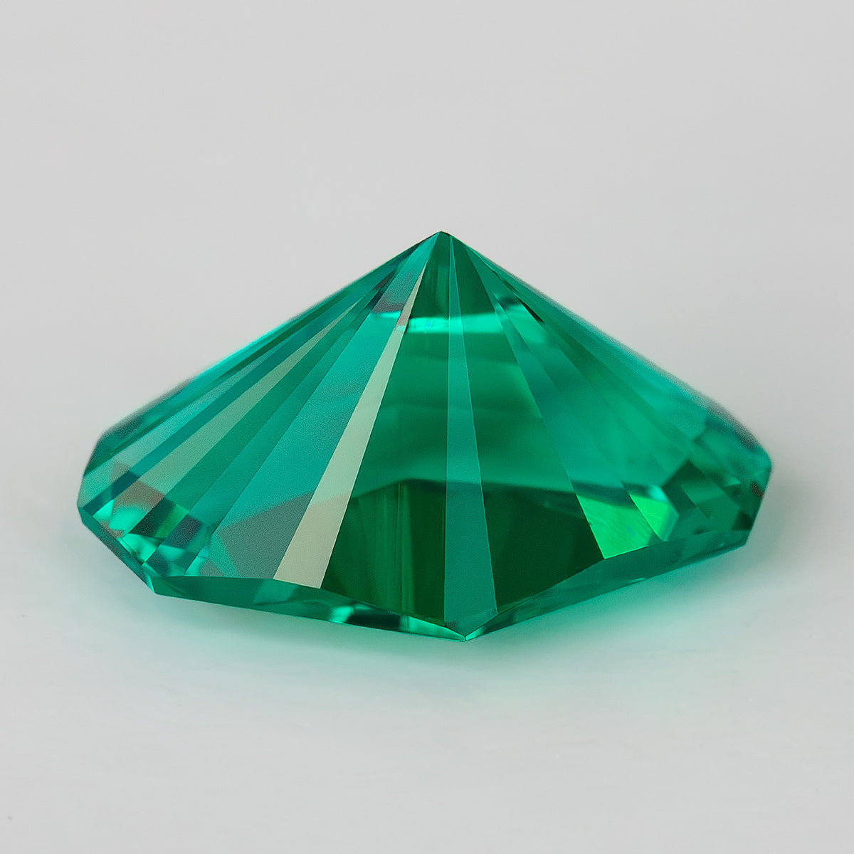 Side and pavilion profile of the green emerald, showing its pointed underside and depth.