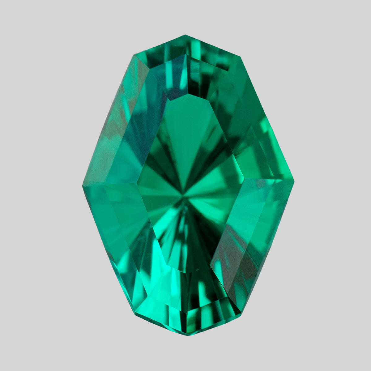 Alternate upright view of the green emerald on white, showing angular central reflections.