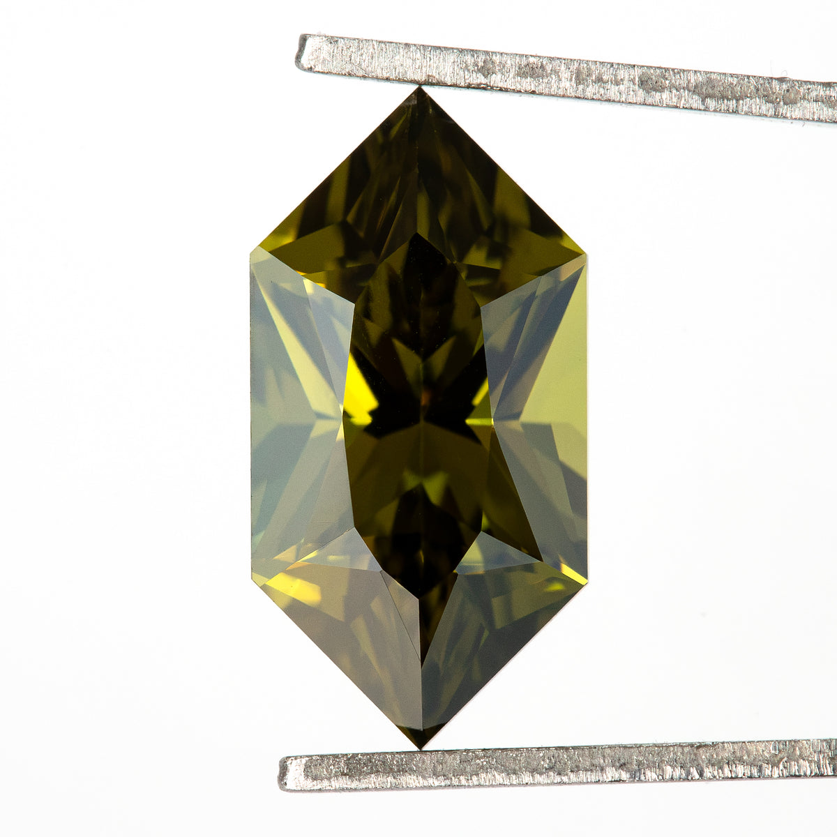 Long hexagonal yellow-green sapphire held upright in tweezers, with dark central reflections.