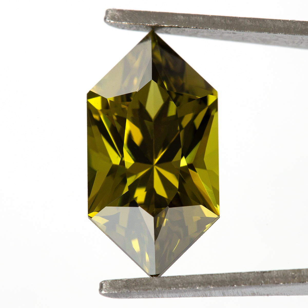 Face-up sapphire in tweezers showing alternating yellow-green and dark geometric facets.