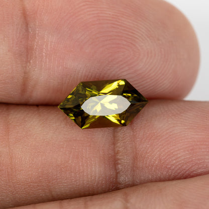 Sapphire on fingers with a broad bright table reflection.