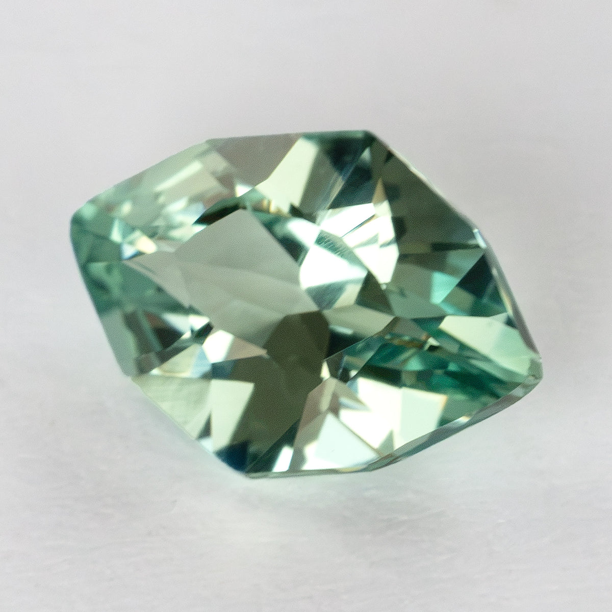 Green lab-grown sapphire in a rotated crown view, with pale central reflections and darker facets.