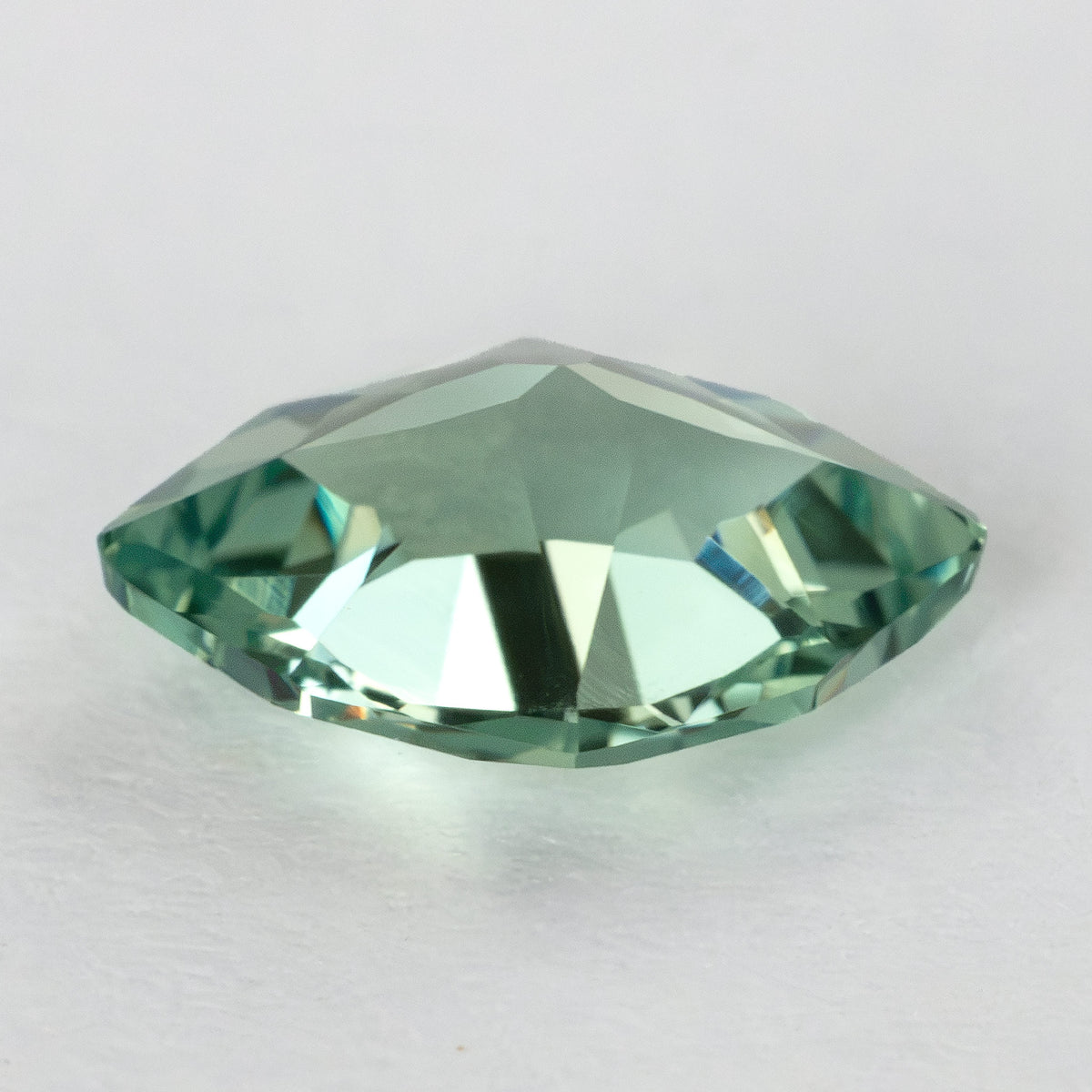 Low-angle profile of the green lab-grown sapphire, showing the raised crown and faceted outline.