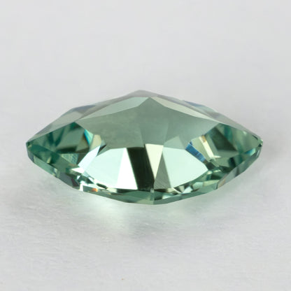 Low-angle profile of the green lab-grown sapphire, showing the raised crown and faceted outline.