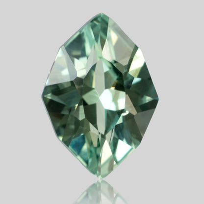 Face-up green lab-grown sapphire standing vertically, with pointed ends and a faint reflection below.