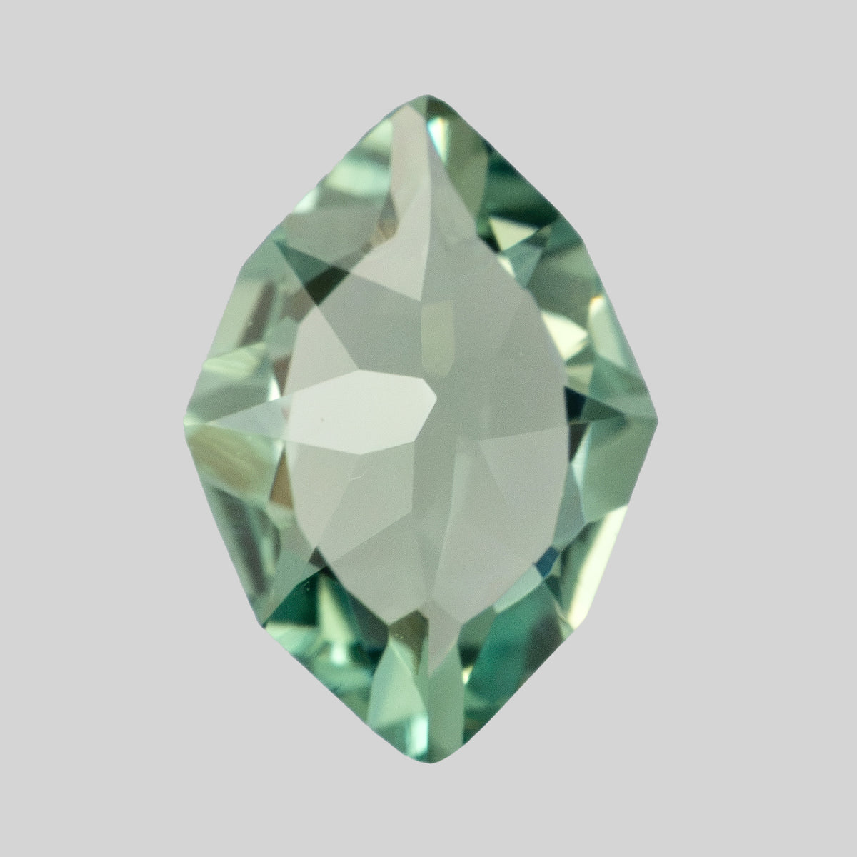 Pavilion-side view of the pale green lab-grown sapphire against a light gray background.