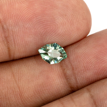 Green lab-grown sapphire resting across fingertips to show its size and face-up appearance.