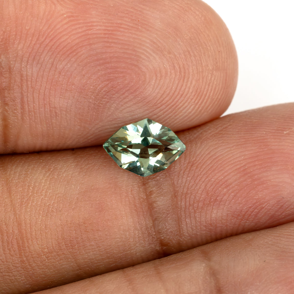 The green lab-grown sapphire on fingertips at another angle, with darker central reflections.