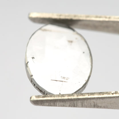 Oval diamond in tweezers at a bright reflective angle.
