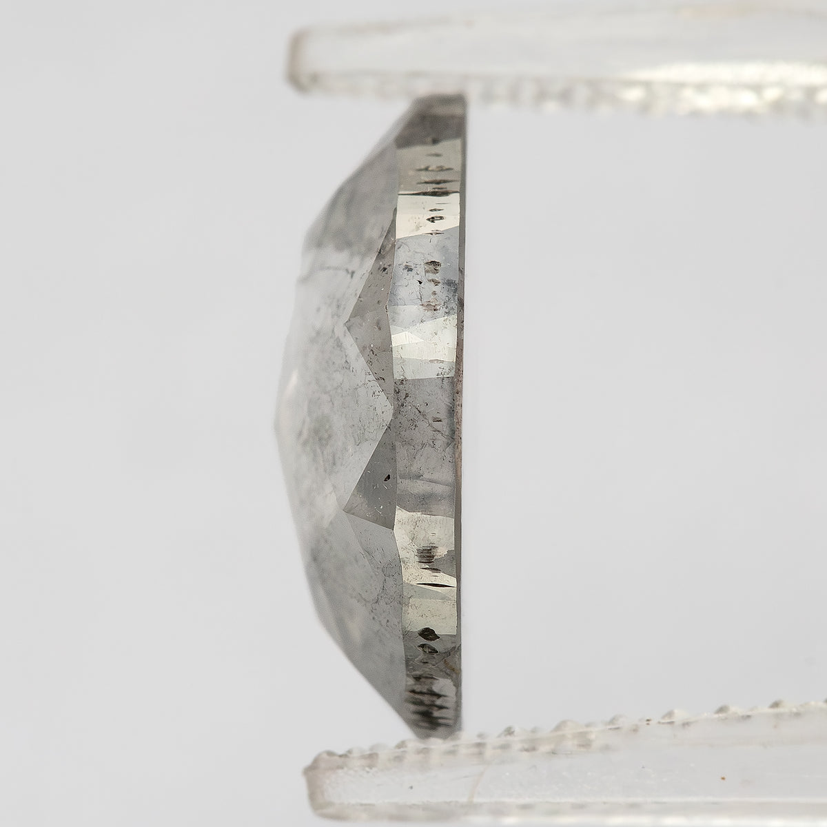Edge-on profile of the oval diamond held in pale tweezers, showing crown height and girdle.