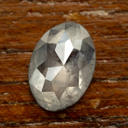 Oval diamond on a warm brown surface, showing a different background behind its inclusions.