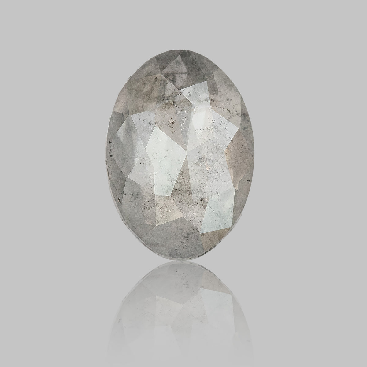 Upright oval diamond on a pale reflective surface, with a faint reflection beneath it.