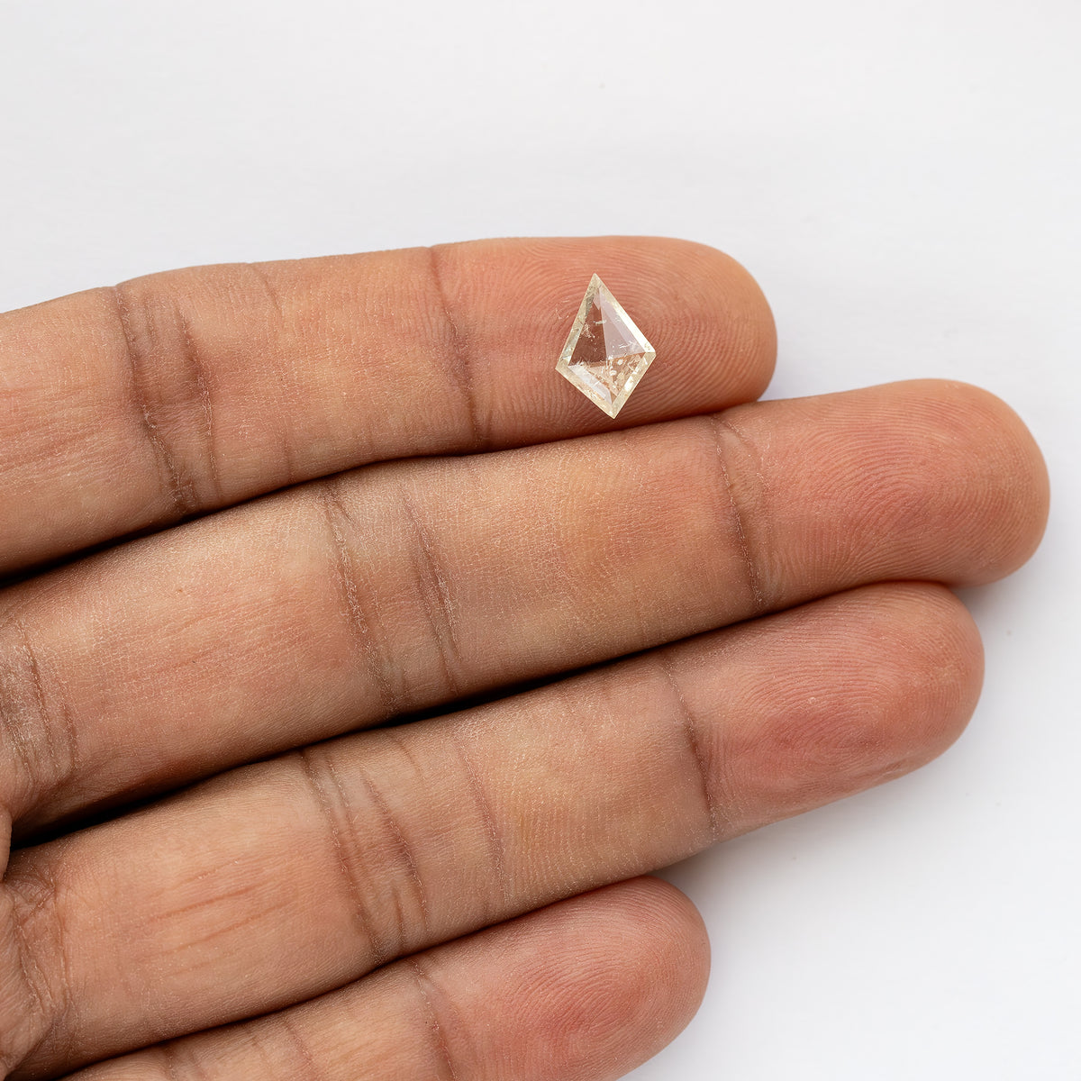 Kite diamond resting across fingertips, with the hand showing its small scale.