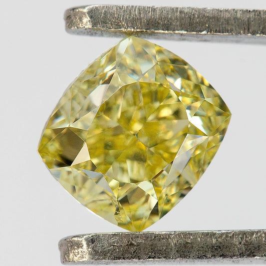 Close face-up view of the exact 0.50 ct natural Fancy Light Yellow cushion modified brilliant diamond held in tweezers.