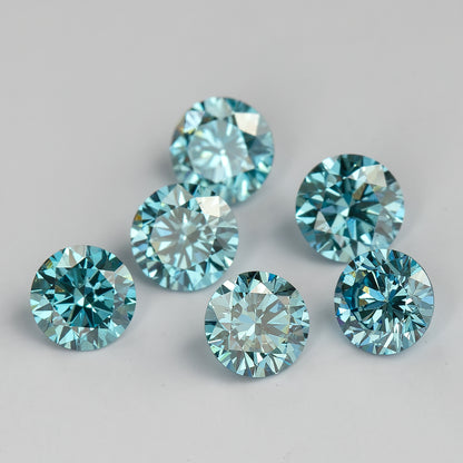 Alternate face-up view of six loose round blue diamonds on a pale surface, showing lighter blue reflections and differences in brightness.