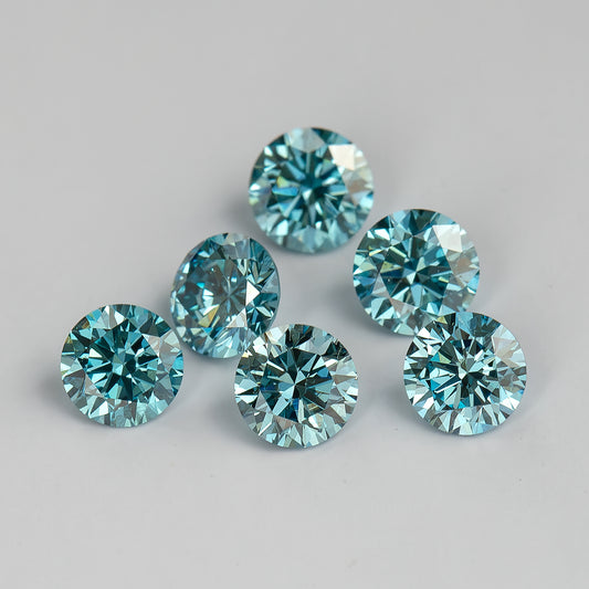 Six round blue diamonds arranged loosely on a pale surface, shown face-up with teal-blue and bright silver facet reflections.