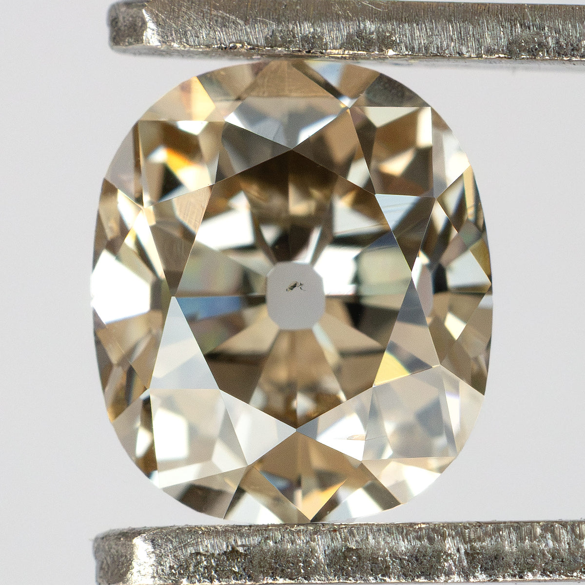 Close-up face-up view of the Old Mine Cut natural diamond held in metal tweezers, showing its facet arrangement.