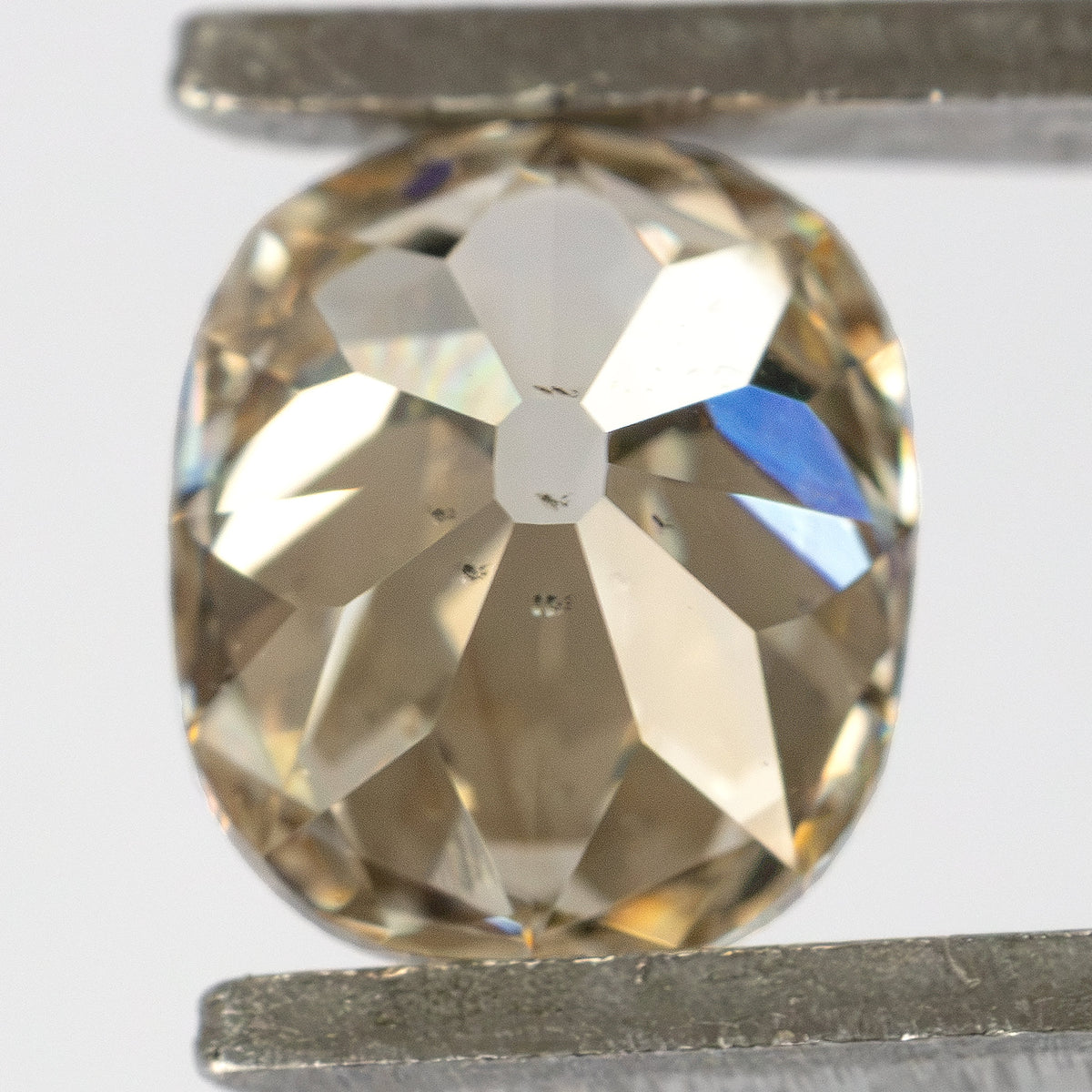 Reverse view of the diamond held in tweezers, showing the pavilion facets and large culet.