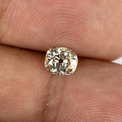 Face-up view of the Old Mine Cut diamond resting between fingertips for a sense of its size.