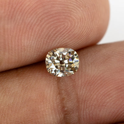 Close-up face-up view of the loose diamond resting on fingers, showing its crown facets and warm appearance.