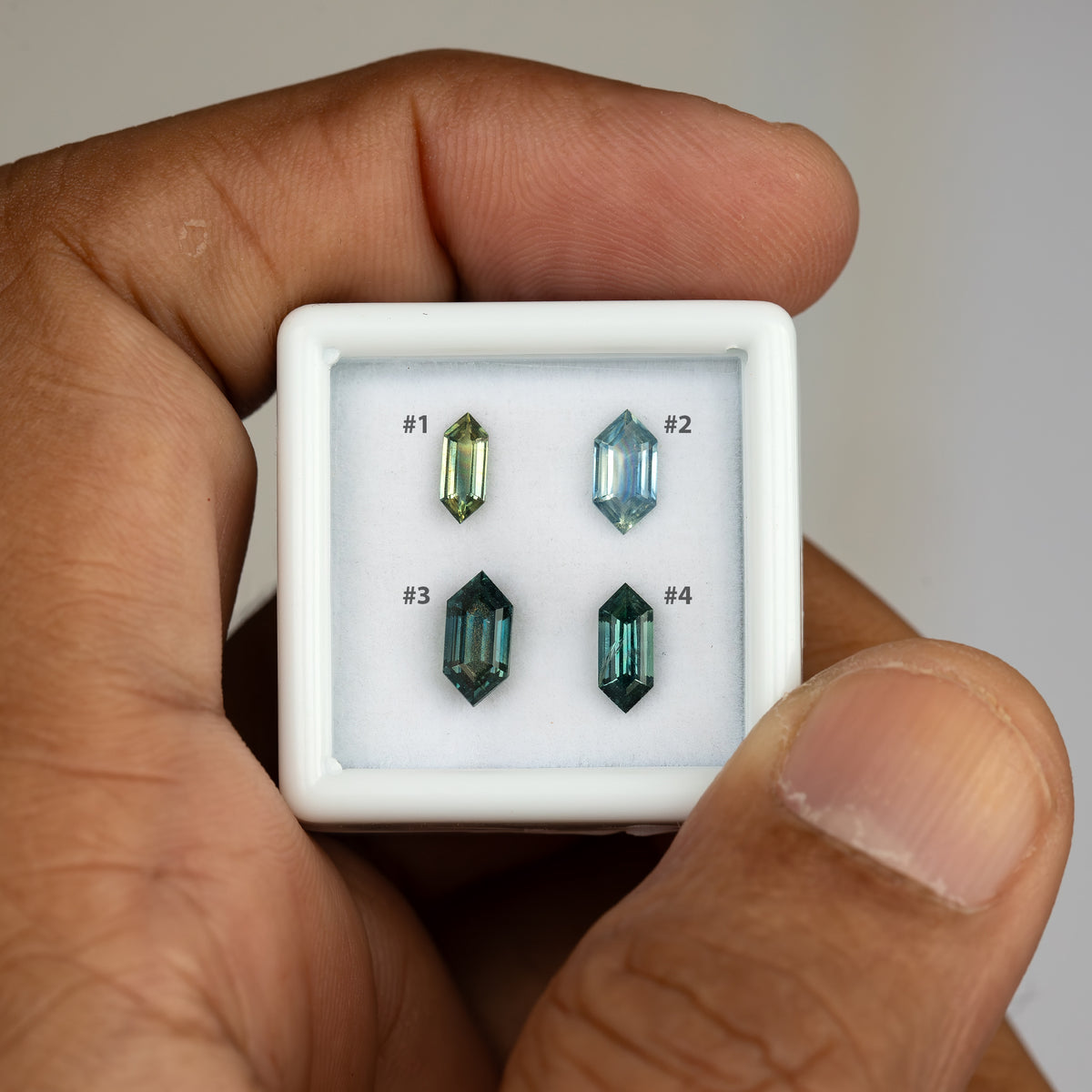 Hand-held numbered view comparing the four exact natural sapphire options.