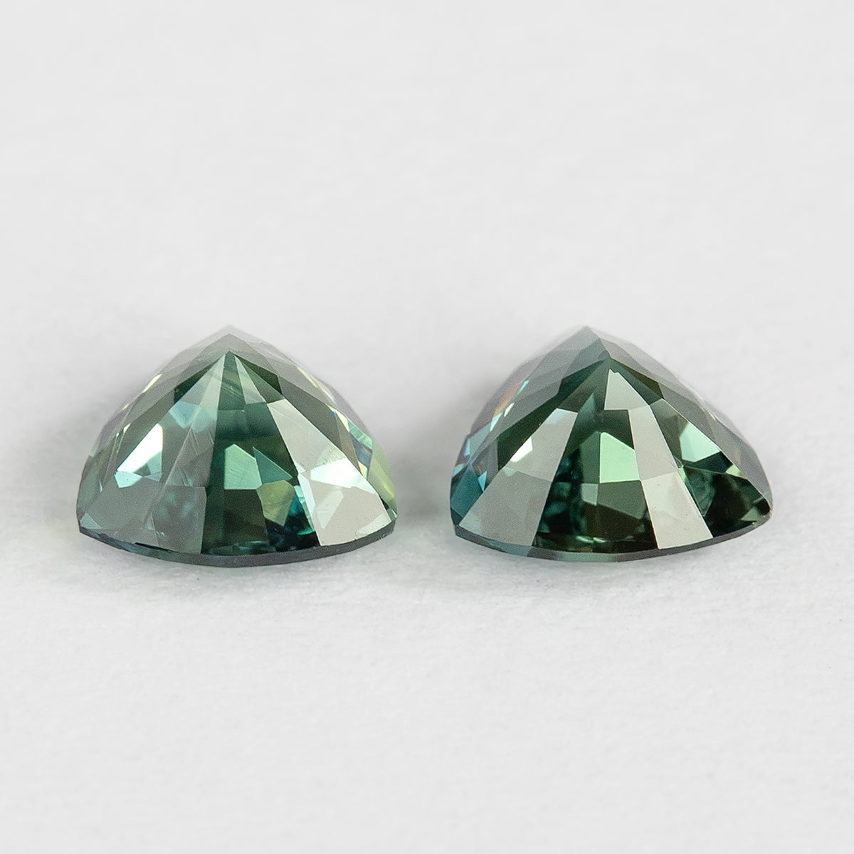 Low side view of the sapphire pair showing pavilion profiles and the different depths of the two loose stones.