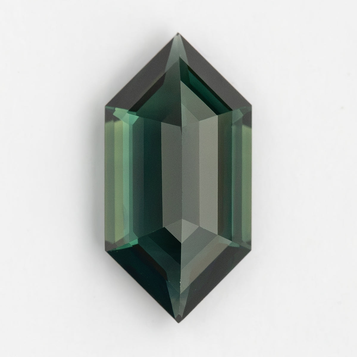 Reverse-side view of the loose green-blue sapphire on a pale background, with pointed ends and alternating light and dark step facets.