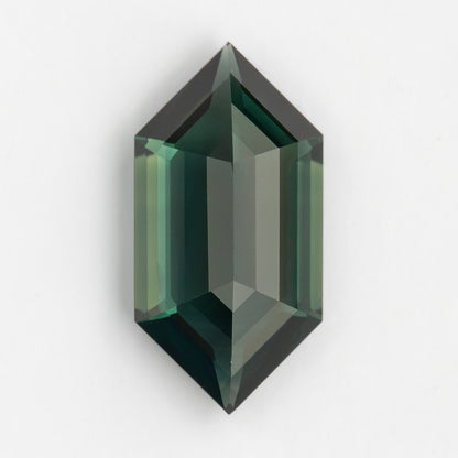 Reverse-side view of the loose green-blue sapphire on a pale background, with pointed ends and alternating light and dark step facets.