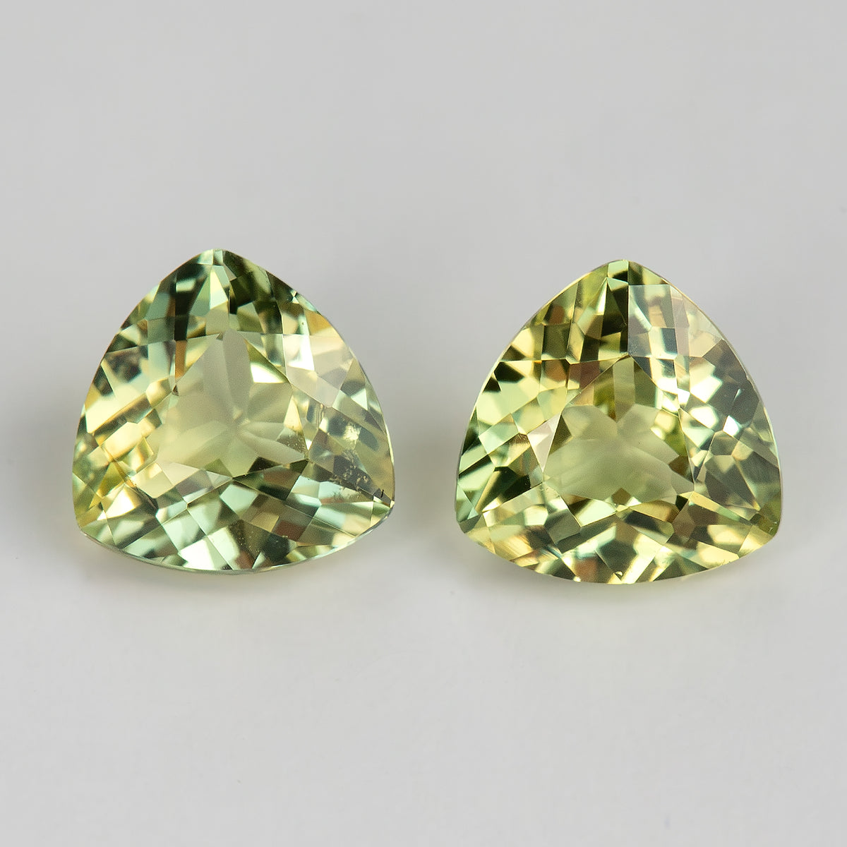 Alternative close-up of both trillion sapphires, showing individual differences in reflected yellow and green tones.