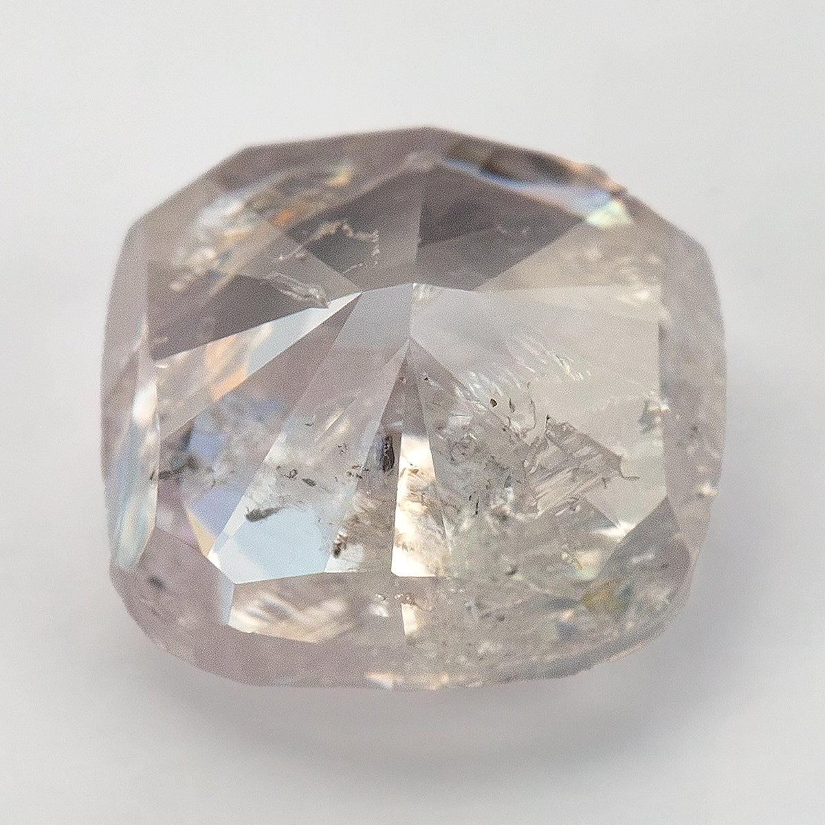Angled face-up macro of the light pink cushion diamond, showing contrasting facets and visible inclusions.