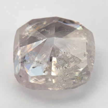 Angled face-up macro of the light pink cushion diamond, showing contrasting facets and visible inclusions.
