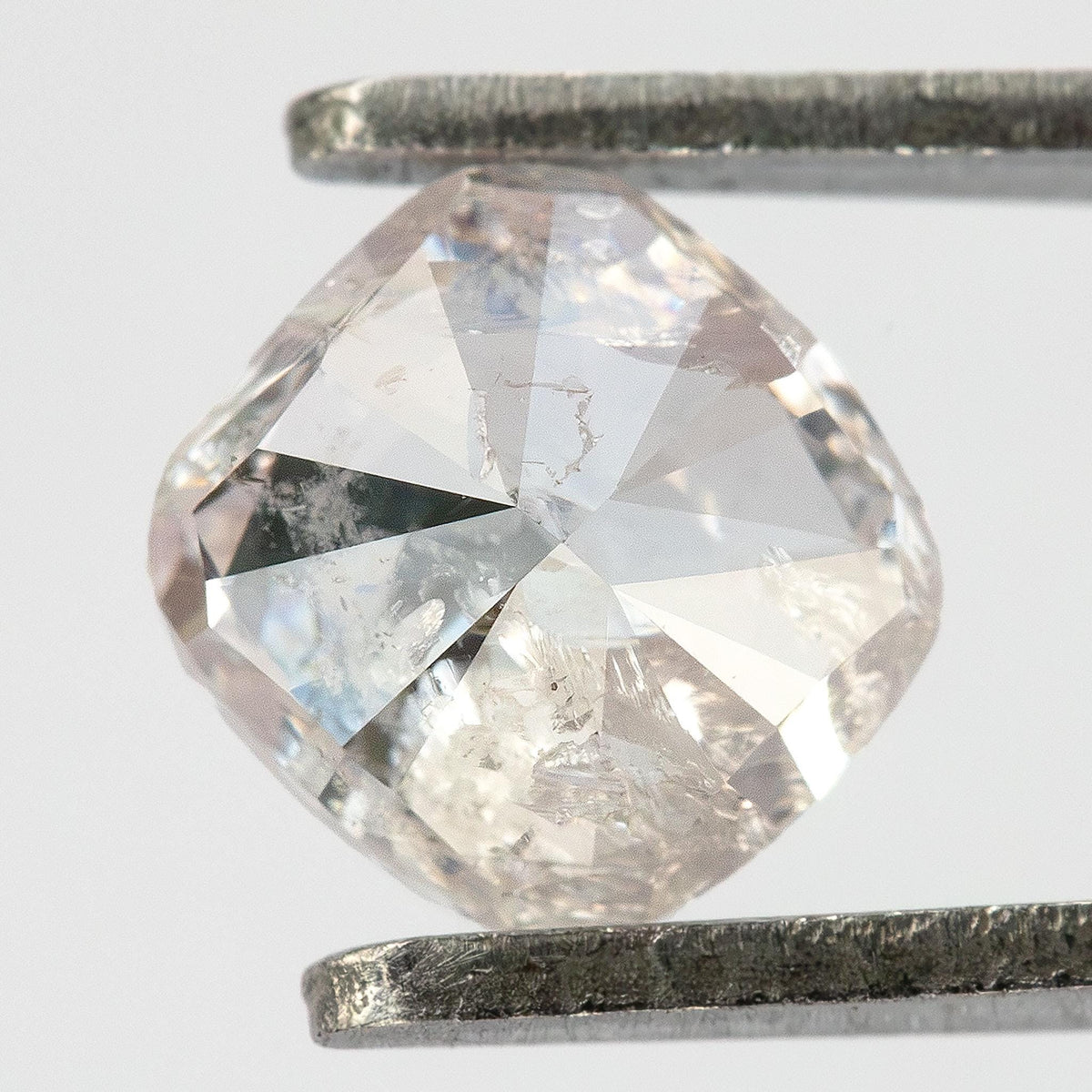 Pavilion view of the natural light pink cushion diamond held in tweezers, showing modified brilliant facets.