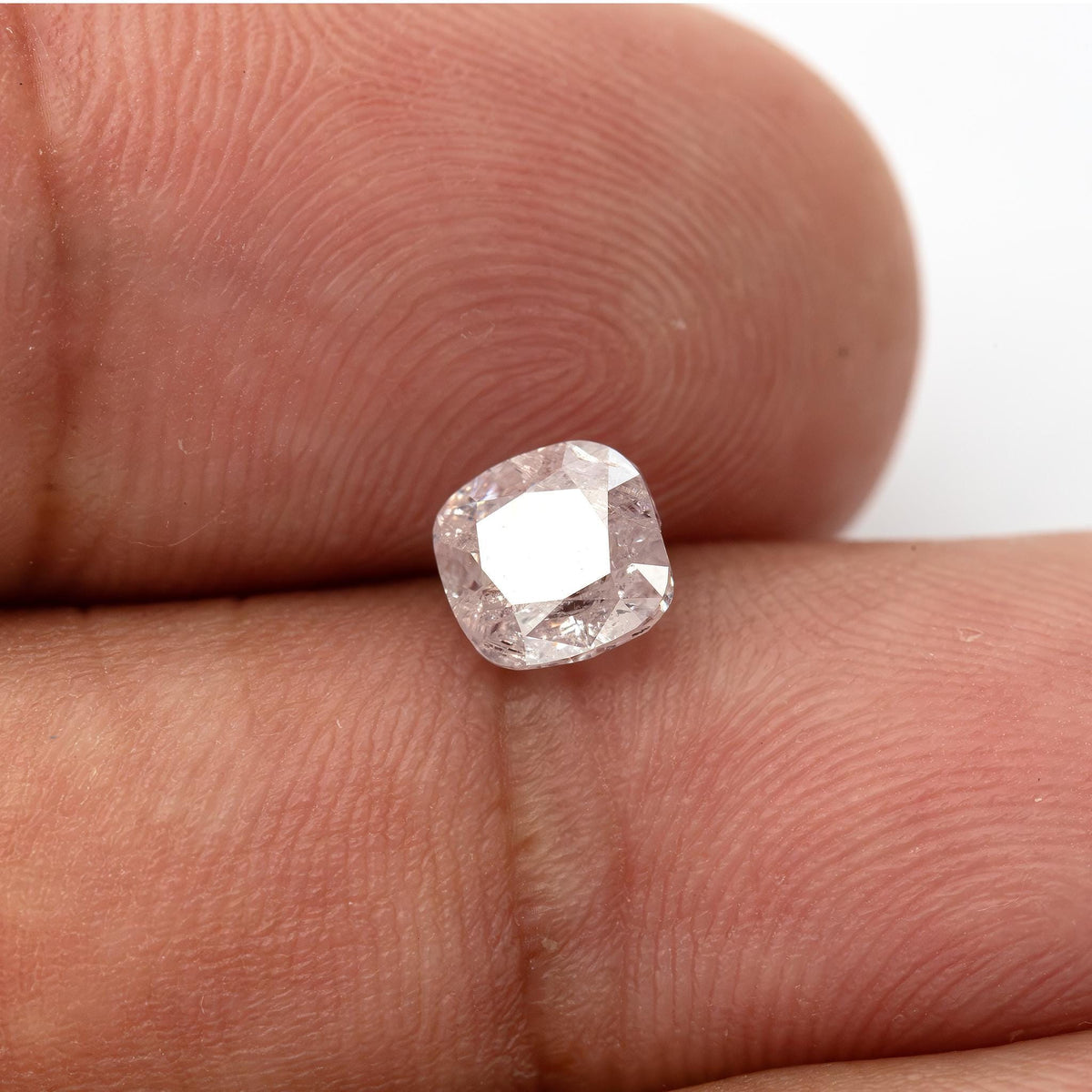 Second fingertip view of the light pink cushion diamond at a brighter reflective angle.