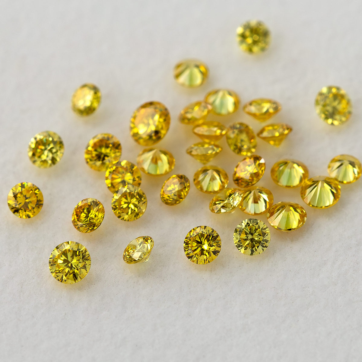 Yellow diamond cluster with several tilted stones and visible pointed pavilions on a pale surface.