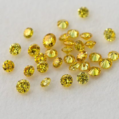Yellow diamond cluster with several tilted stones and visible pointed pavilions on a pale surface.