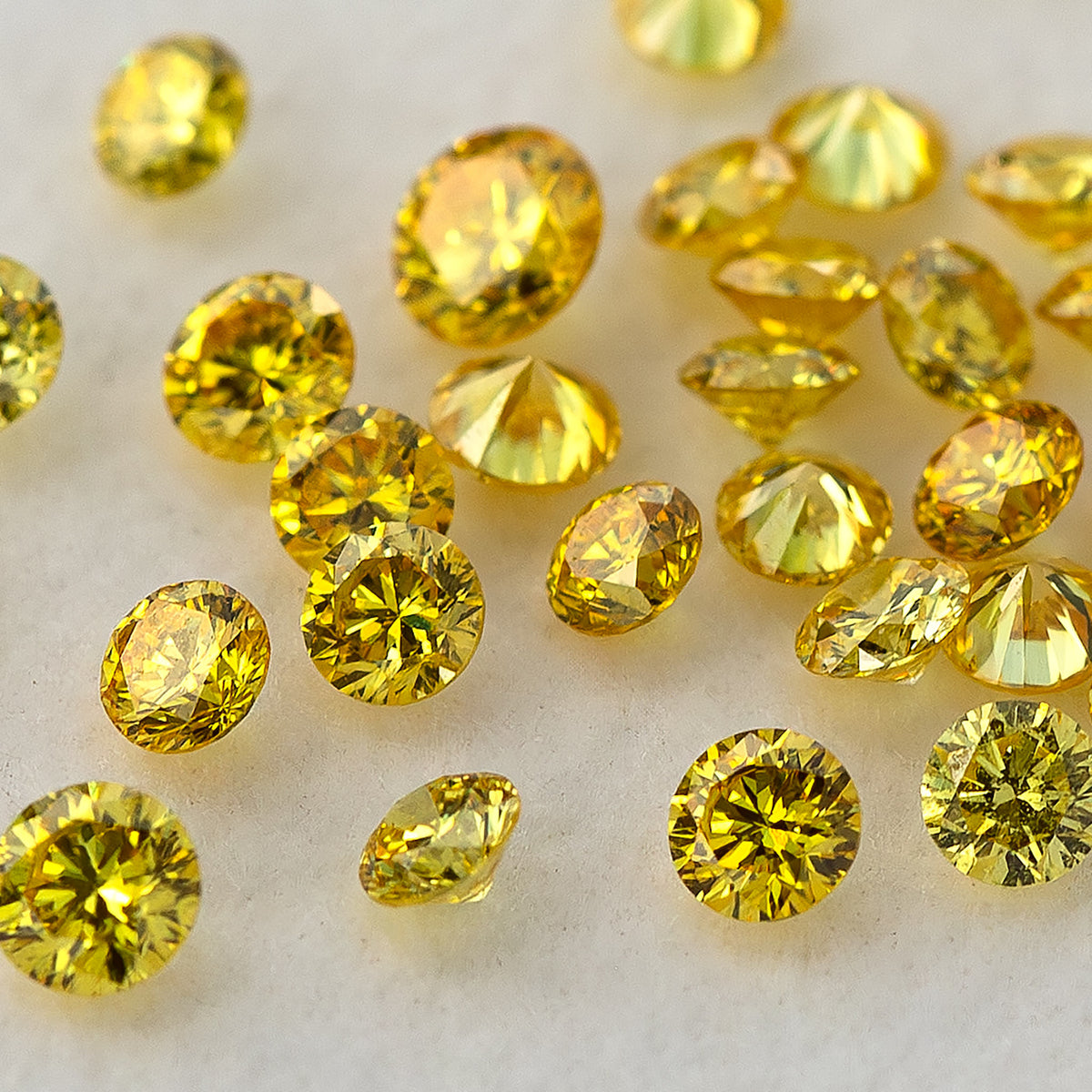 Closer tilted cluster of yellow diamonds showing crowns, girdles and pavilions.