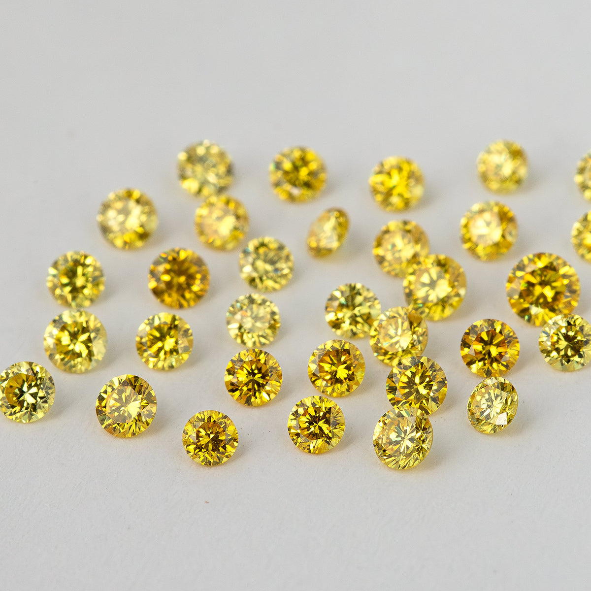 Wider low-angle view across loose yellow diamonds on a pale background.