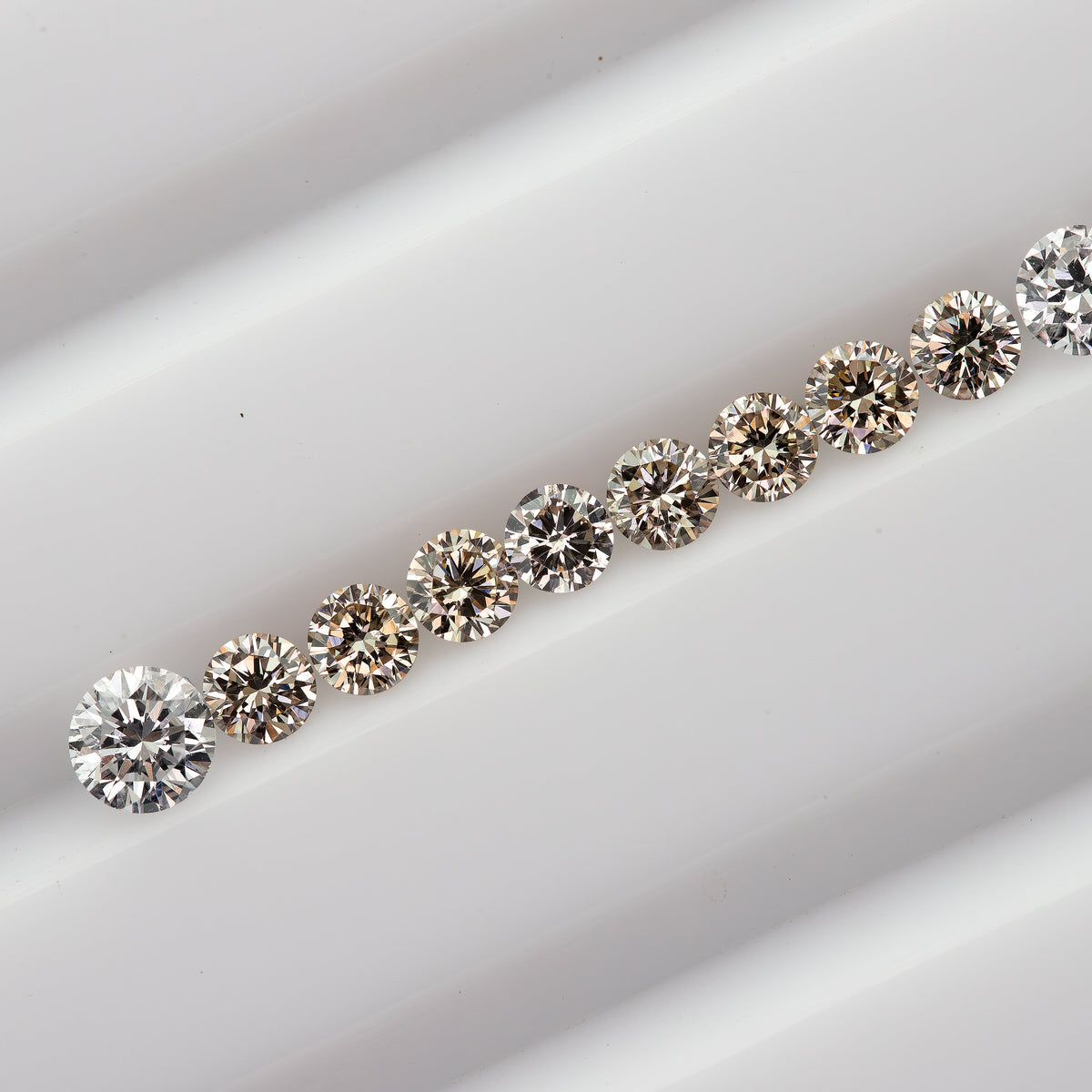 Diagonal row of representative 2.5mm champagne round diamonds with white comparison stones not included.