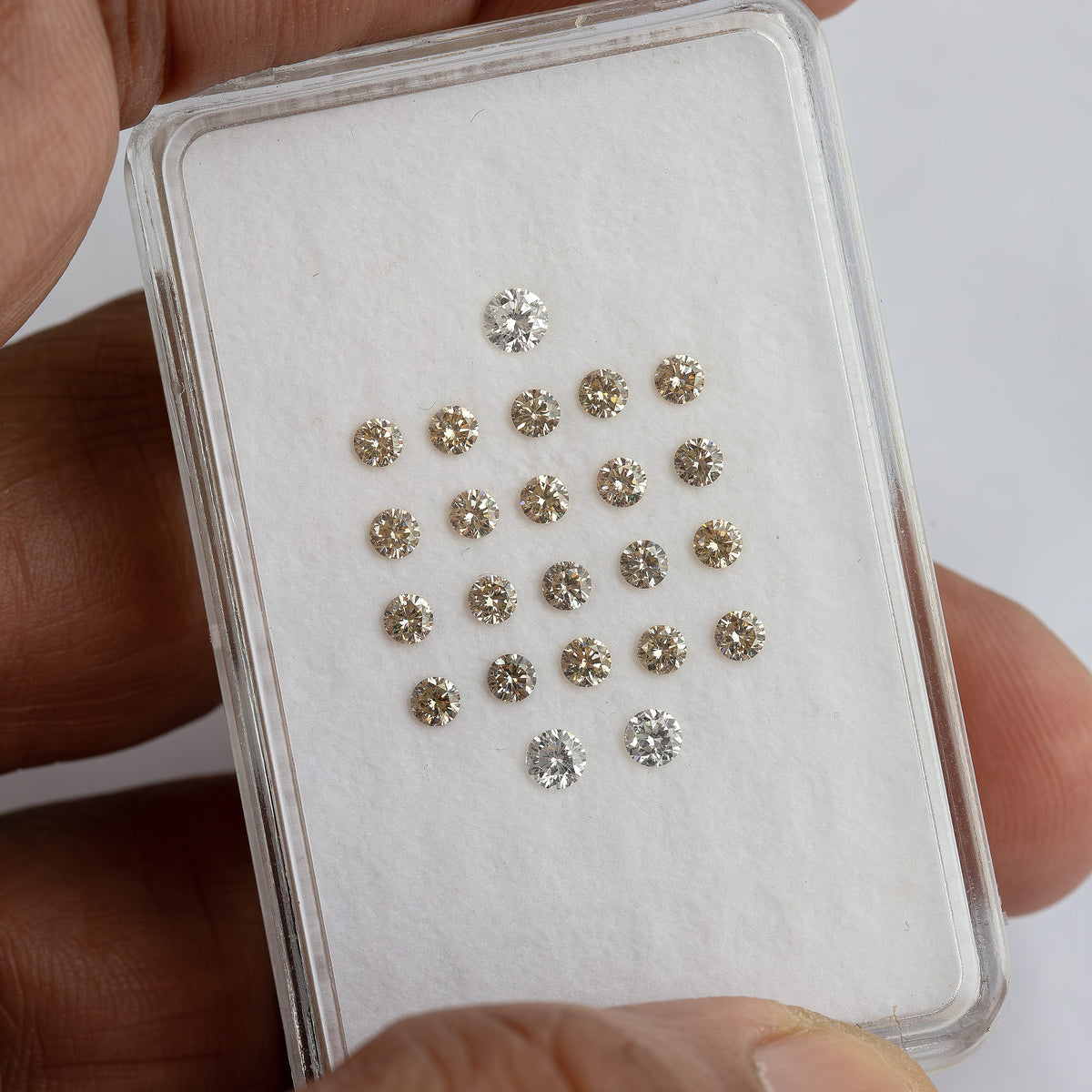 Hand view of representative champagne round diamond stock; exact selected pack is supplied.