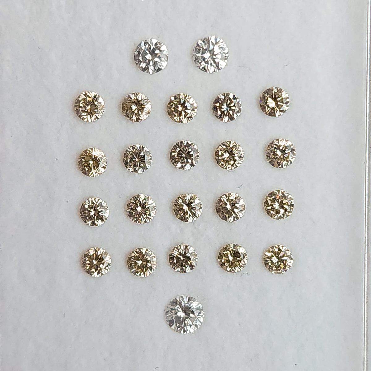 Close view of representative 2.5mm champagne diamond melee in a clear parcel box.