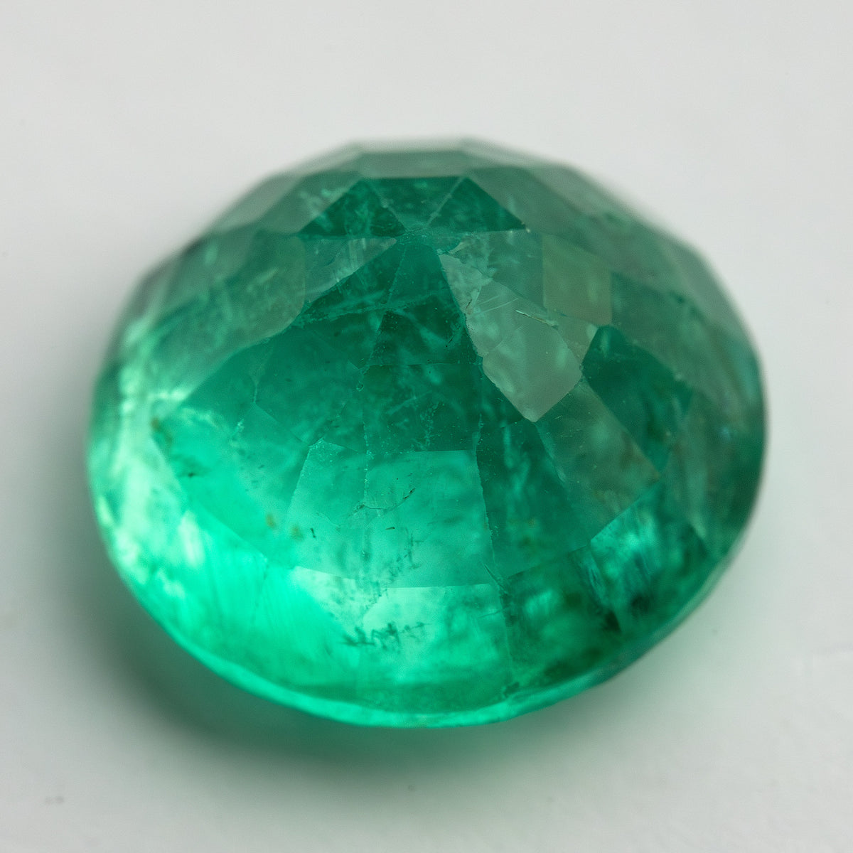 Angled reverse view of the round green emerald on white, showing the domed pavilion.
