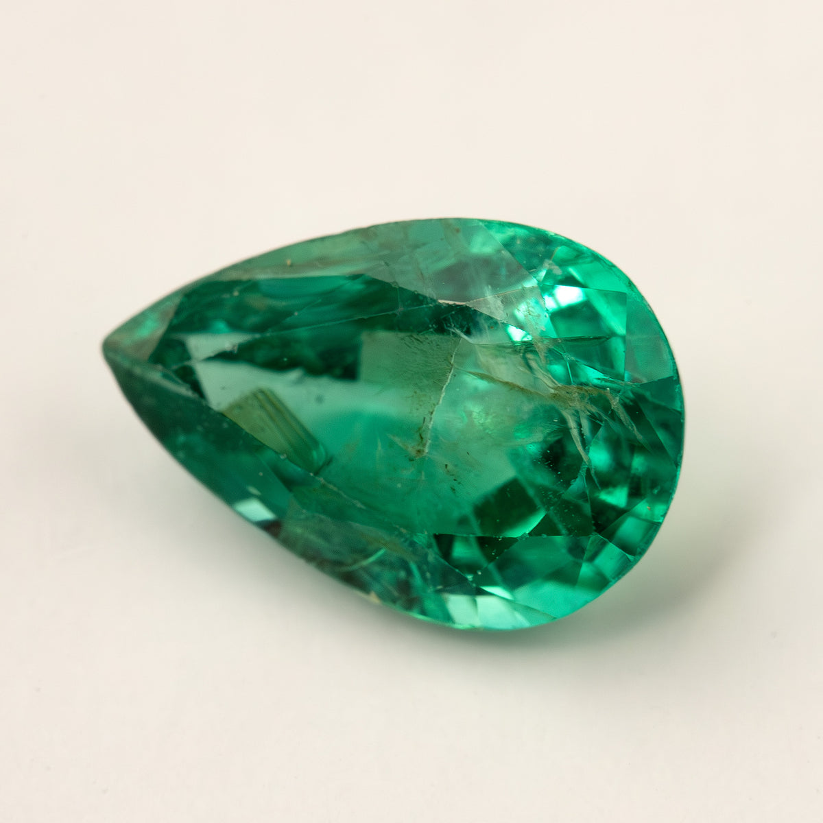 Pear emerald lying face-up on a pale surface from a lower angle.